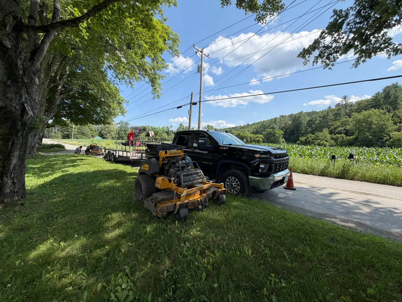 Eagle Lawn truck and equipment trailer parked beside a Vermont roadside property