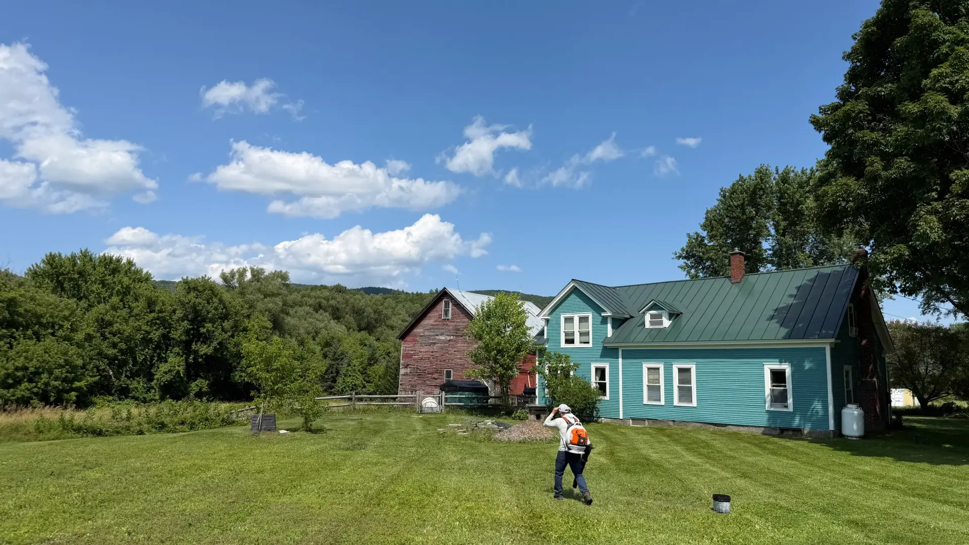 A Vermont farmhouse and barn above a wide mown lawn in the Mad River Valley