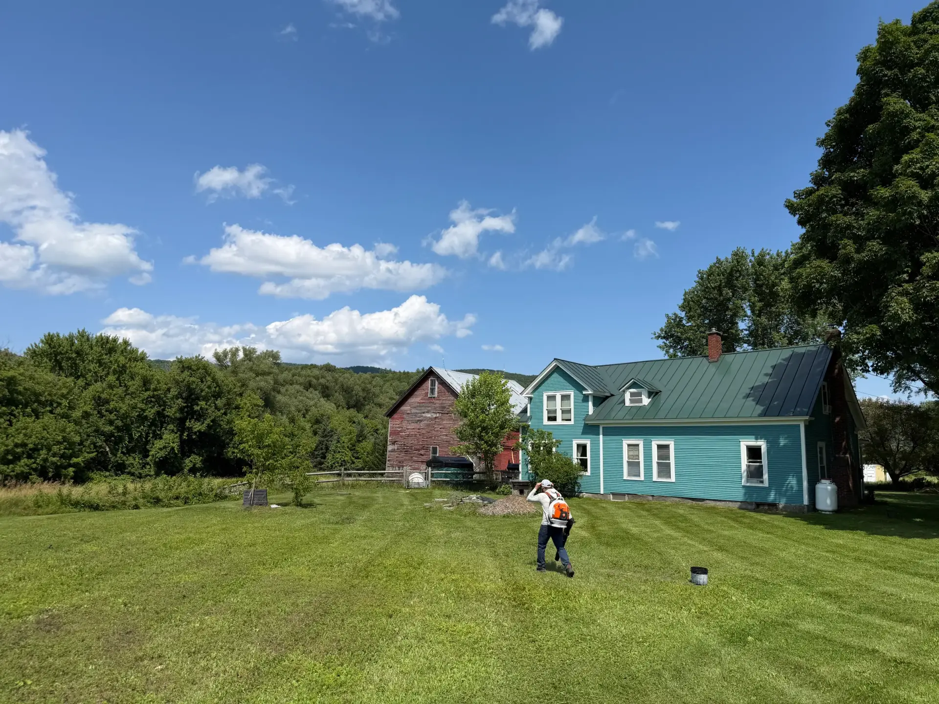 A Vermont property with a long open driveway and a barn, viewed across the lawn